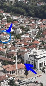 een stad met gebouwen en een toren met blauwe pijlen bij Guesthouse "PELIVANI" in Berat