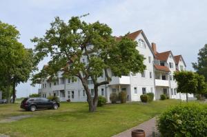 una gran casa blanca con un coche aparcado delante de ella en Fewo im Kastania Nr19, en Petersdorf auf Fehmarn