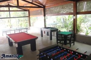 two ping pong tables in a room with windows at Amarilis Flat Service in Riviera de São Lourenço