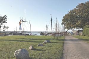 a path next to a field with boats in the water at FeWo Kranich in Fuhlendorf