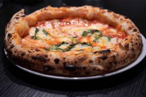 a pizza sitting on a plate on a table at Hotel Vittorio Veneto Napoli in Naples