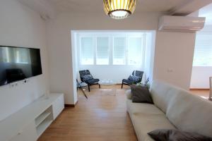salon z kanapą i telewizorem z płaskim ekranem w obiekcie Apartamento Mercedes Céntrico Playa w mieście Sanlúcar de Barrameda