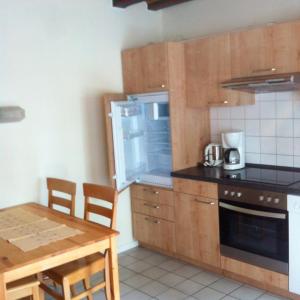 a small kitchen with a table and a refrigerator at Ferienhof Bisdorf "Lunauhaus" Reihenhaus in Bisdorf