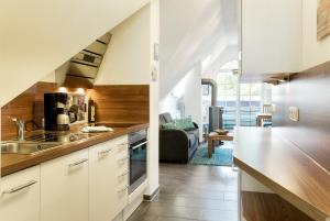 een keuken met witte kasten en een woonkamer bij Villa Obendtied, DG-Wohnung "Reet" FW 6 in Zingst