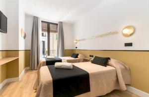a room with two beds and a tv at Cálamo Guesthouse in Madrid
