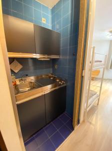 una pequeña cocina con fregadero y azulejos azules en Residence Foemina 65 Val di Luce en Abetone