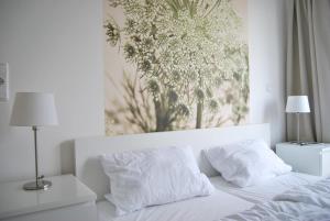 ein weißes Bett mit zwei Kissen und einem Gemälde an der Wand in der Unterkunft Fehmarn-OstseeferienStrandresidenz Vogelflug, App 17 in Fehmarnsund
