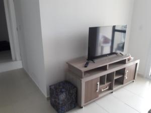 uma televisão de ecrã plano sentada num centro de entretenimento em APTO 02 DORM BERTIOGA em Bertioga
