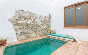 una piscina con un banco junto a una pared de piedra en Encantadora casa rural con piscina privada, en El Bosque