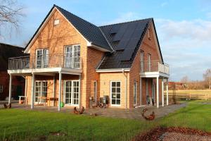 een groot bakstenen huis met zonnepanelen erop bij Herrmannshof Haby App 1 Arnis in Haby