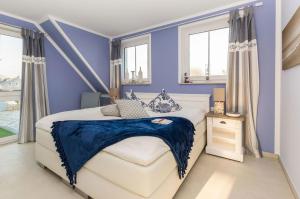 a blue bedroom with a white bed and windows at Whg 15 - Strandläufer in Zingst