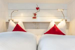 two beds with red pillows in a hotel room at Komfortferienwohnung "Idylle" in Schwaigs