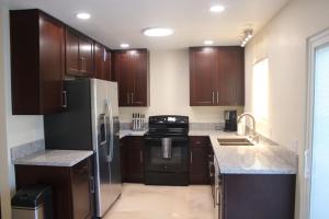 a kitchen with wooden cabinets and a black refrigerator at Newly Remodeled Family Friendly 3B/2B House in Henderson