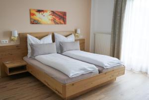 ein Schlafzimmer mit einem großen Bett mit weißer Bettwäsche und Kissen in der Unterkunft Pension Paßler in Seeboden
