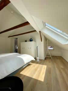 a bedroom with a white bed and a skylight at Loft an der Seefahrtschule in Großefehn 