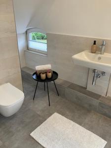 a bathroom with a toilet and a sink and a table at Loft an der Seefahrtschule - Timmel in Großefehn 