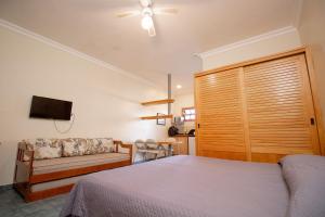 1 dormitorio con 1 cama y 1 sofá en Ilha Flat Hotel, en Ilhabela
