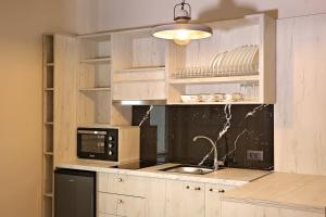 a kitchen with wooden cabinets and a black microwave at Ares Suites in Plataria