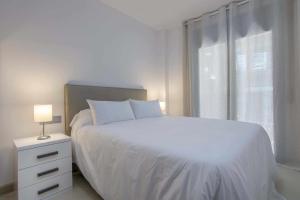 a white bedroom with a bed and a window at Apartamento Arbones de Manresa in Manresa