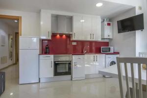 a kitchen with white appliances and a red wall at Apartamento Arbones de Manresa in Manresa