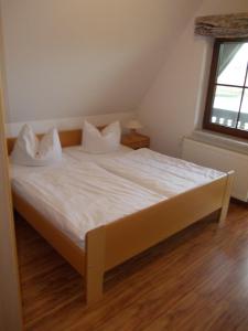 - un lit avec des draps et des oreillers blancs dans l'établissement Finnhäuser am Vogelpark - Haus Annika, à Marlow