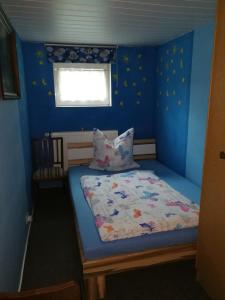 ein kleines Schlafzimmer mit einem Bett in einem blauen Zimmer in der Unterkunft Ferienwohnung Stoll in Brüel