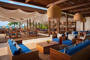 un restaurante en la playa con sillas y mesas azules en Secrets Maroma Beach Riviera Cancun - Adults only en Playa del Carmen