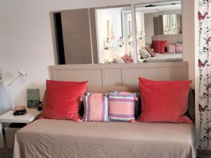 ラスパルマス・デ・グランカナリアにあるApartamento Toñiのベッドルーム1室(赤い枕と鏡付きのベッド1台付)