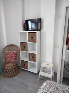 ラスパルマス・デ・グランカナリアにあるApartamento Toñiのテレビ、椅子、棚が備わる客室です。