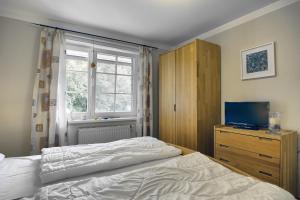 1 dormitorio con 1 cama, TV y ventana en Mücke, Christian, en Zingst