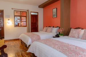Duas camas num quarto com paredes cor de laranja em Rincón Familiar Hostel Boutique em Quito