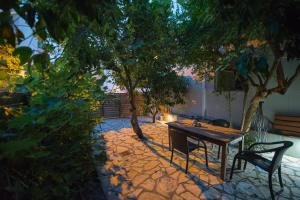 un tavolo e una panchina in un cortile alberato di Casa Dina a Città di Lefkada