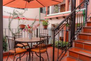 a table and chairs on a balcony with an umbrella at Rincón Familiar Hostel Boutique in Quito