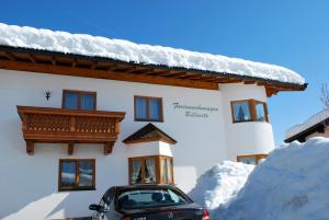 a car parked in front of a building with snow at Ferienwohnungen Billovits in Kössen