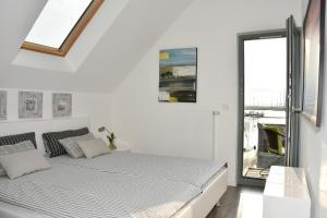 a white bedroom with a bed and a window at Ostsee - Appartement Nr 22 "Ankerplatz" im Strand Resort in Heiligenhafen