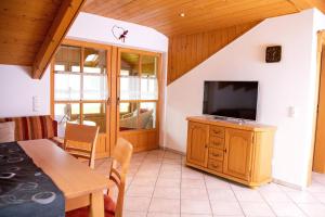 ein Wohnzimmer mit einem TV und einem Esstisch in der Unterkunft Ferienwohnung "Panoramablick" in Achslach