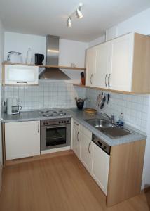 a kitchen with white cabinets and a sink at Likedeeler Weg 1 Whg 18 in Zingst