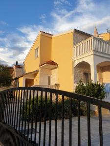 una casa gialla con una recinzione nera di Apartments CroatiaSun a Vodice