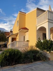 una casa gialla con un balcone bianco su una strada di Apartments CroatiaSun a Vodice