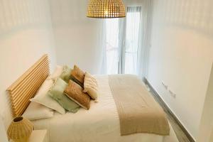 sypialnia z łóżkiem z poduszkami i oknem w obiekcie Precioso apartamento con vistas parciales, garaje y piscina w mieście Tarifa +11 zdjęć