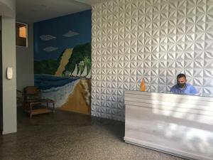 a man sitting at a counter in a room with a painting at Atlântico Flat 209 in Natal