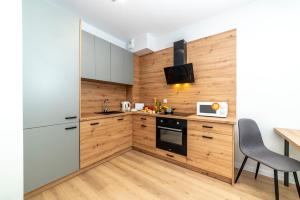 cocina con electrodomésticos blancos y paredes de madera en Apartamenty Przy IV Śluzie - Gold, en Bydgoszcz