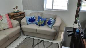 ein Wohnzimmer mit Sofa und blauen Kissen in der Unterkunft Lindo Apartamento Enseada in Guarujá