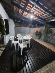 un patio con sillas blancas, mesa, mesa y sillas en Casa FLORIANÓPOLIS, Praia de PONTA DAS CANAS,1, en Florianópolis