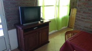 a tv sitting on a wooden cabinet with a table at Abuelo Coqui in Ramallo