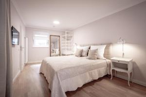 a white bedroom with a large bed and a table at Boutique Charme Apartments in Baden-Baden