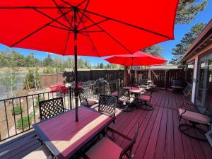 eine Terrasse mit Tischen, Stühlen und roten Sonnenschirmen in der Unterkunft Estes Mountain Inn in Estes Park