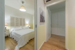 a white bedroom with a bed and a mirror at APPARTAMENTO VILLAGGIO CASCINA - JESOLO in Lido di Jesolo