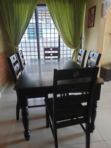 a black dining room table and chairs with a window at Roemahkoe Holidayhome in Malacca