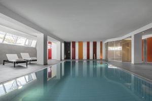 a swimming pool in a building with a lobby at Hotel Krondlhof in Brunico